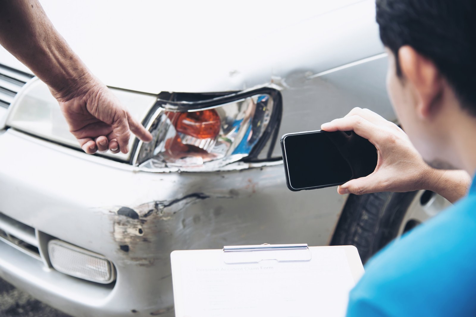 man-holding-mobile-phone-paper-by-customer-showing-damaged-car
